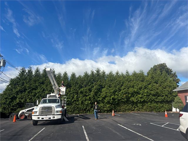 Bucket truck and skidsteer working in a parking lot